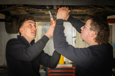 Twee monteurs werken samen onder een auto