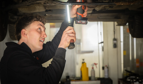 Monteur aan het werk onder een auto met boormachine