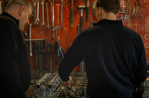 Henk en Job werken aan een open motorblok bij de gereedschapswand